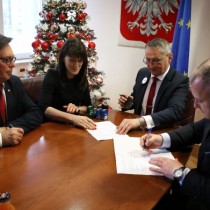 Powiększ zdjęcie Przy stole od prawej siedzą: Wicestarosta Włoszczowski Łukasz Karpiński podpisuje druk umowy, Wojewoda Świętokrzyski Zbigniew Koniusz, Skarbnik Powiatu Agnieszka Górska, Starosta Włoszczowski Dariusz Czechowski. 