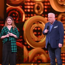 Powiększ zdjęcie Od lewej w zielono czarnej koszuli w kratę Katarzyna Mazur, a obok  na scenie z mikrofonem Marek Sierocki prowadzący program.dcinka „Szansy na sukces ”.