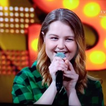 Powiększ zdjęcie Katarzyna Mazur z mikrofonem podczas nagrania odcinka „Szansy na sukces ”.