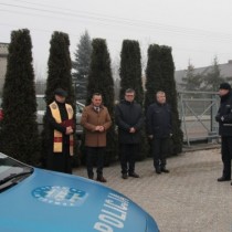 Powiększ zdjęcie Na pierwszym planie fragment nowego radiowozu. W tle od prawej strony stoją: Ksiądz Kanonik Leszek Dziwosz, Burmistrz Grzegorz Dziubek, Starosta Dariusz Czechowski, Wójt Secemina Tadeusz Piekarski, Komendant Policji  insp. Mariusz Przyborowski.