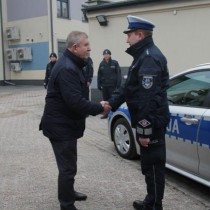 Powiększ zdjęcie Wójt Gminy Secemin Tadeusz Piekarski ( po prawej)  gratuluje przedstawicielowi włoszczowskich policjantów. W tle nowy radiowóz i obecni na uroczystości policjanci.