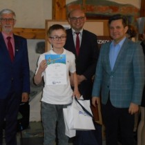 Powiększ zdjęcie Od lewej stoją: Senator Jacek Włosowicz, dyrektor Sylwester Kasprzyk, laureat konkursu trzyma dyplom i torebkę z upominkiem, wizytator Świętokrzyskiego Kuratorium Oświaty Sławomir Krzysztofik.