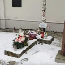 Powiększ zdjęcie Symboliczny grób błogosławionego ks. Jerzego Popiełuszki przy kościele Wniebowzięcia Najświętszej Maryi Panny we Włoszczowie. Na kamiennym postumencie w kształcie krzyża kwiaty i znicze.