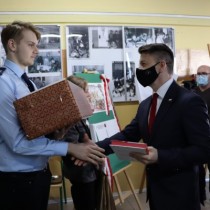 Powiększ zdjęcie Poseł Bartłomiej Dorywalski (z prawej) wręcza książkę zdobywcy II miejsca w konkursie “Kartka okolicznościowa - 37. Rocznica Protestu o Krzyże w Zespole Szkół Zawodowych we Włoszczowie” Radoszowi Jachymowi (po lewej).