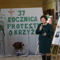 Powiększ zdjęcie Uczestniczka strajku trzyma mikrofon, przemawia do zebranych uczestników uroczystości z okazji 37. rocznicy protestu o krzyże w Zespole Szkół Zawodowych we Włoszczowie