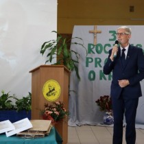 Powiększ zdjęcie Wizytator Kuratorium Oświaty w Kielcach Sławomir Krzysztofik trzyma mikrofon, przemawia do zebranych uczestników uroczystości z okazji 37. rocznicy protestu o krzyże w Zespole Szkół Zawodowych we Włoszczowie.