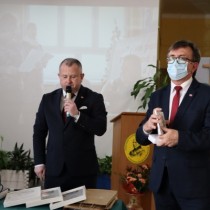 Powiększ zdjęcie Od lewej Wicestarosta Włoszczowski Łukasz Karpiński, trzyma mikrofon, przemawia do zebranych uczestników uroczystości z okazji 37. rocznicy protestu w Zespole Szkół Zawodowych. Obok Starosta Dariusz Czechowski trzyma jubileuszowe kartki pocztowe.