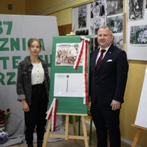 Powiększ zdjęcie W środku sztaluga z makietą kartki jubileuszowej z okazji 37. rocznicy protestu o krzyże we Włoszczowie. Po prawej stronie Wicestarosta Włoszczowski Łukasz Karpiński, po lewej Oliwia Mazur autorka zwycięskiej grafiki na kartce.