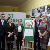 Powiększ zdjęcie Od lewej stoją Wojciech Stelmach, Dorota Cieśla, Oliwia Mazur w środku sztaluga z makietą jubileuszowej kartki pocztowej, Andrzej Książek i Dorota Lipka.