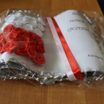 Powiększ zdjęcie Laurka w kształcie księgi wykonana przez KGW Bieganów. Z lewej strony biało - czerwona flaga wykonana z kwiatów z bibuły, z prawej strony Biało czerwona szarfa i napis: BÓG, HONOR, OJCZYZNA i KGW Bieganów.