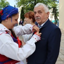 Powiększ zdjęcie Dekoracja kotylionem dożynkowym przewodniczącego Rady Powiatu Włoszczowskiego Zbigniewa Matyśkiewicza.