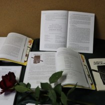 Powiększ zdjęcie Finał X Międzyszkolnego Konkursu Poetyckiego im. Łukasza Uniejewskiego. Na stoliku leżą otwarte książki, a między nimi leży czerwona róża.