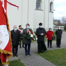 Powiększ zdjęcie Kwiaty pod pomnikiem składają od lewej:  Wicestarosta Łukasz Karpiński, Starosta Włoszczowski Dariusz Czechowski, Proboszcz Parafii Wniebowzięcia NMP we Włoszczowie ks. prałat Zygmunt Pawlik.