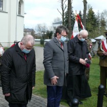 Powiększ zdjęcie Kwiaty pod pomnikiem składają od lewej:  Wicestarosta Łukasz Karpiński, Starosta Włoszczowski Dariusz Czechowski, Proboszcz Parafii Wniebowzięcia NMP we Włoszczowie ks. prałat Zygmunt Pawlik.