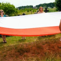 Powiększ zdjęcie Nauczyciele i uczniowie z Dobromierza trzymają wielką flagę narodową