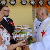 Powiększ zdjęcie Starostowie dożynek przekazują księdzu chleb i kosz owoców do poświęcenia
