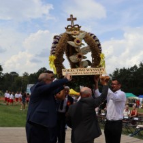 Powiększ zdjęcie Władze Powiatu Włoszczowskiego i Gminy Krasocin podnoszą wieniec wykonany przez KGW Występy