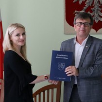 Powiększ zdjęcie Starosta Włoszczowski Dariusz Czechowski przekazuje jeden egzemplarz podpisanej umowy Katarzynie Kmicie – właścicielce Przedsiębiorstwa Handlowo-Usługowego „KAMI” z Kurzelowa