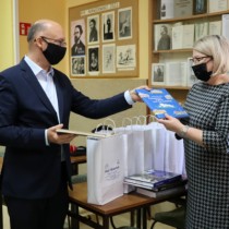 Powiększ zdjęcie Minister Piotr Wawrzyk przekazuje książki Kierownik Wojewódzkiej Biblioteki Pedagogicznej w Kielcach Filii we Włoszczowie Justynie Kowalskiej 