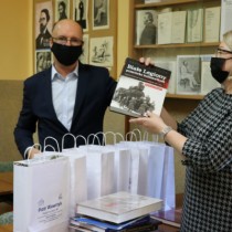 Powiększ zdjęcie Minister Piotr Wawrzyk przekazuje książki Kierownik Wojewódzkiej Biblioteki Pedagogicznej w Kielcach Filii we Włoszczowie Justynie Kowalskiej 